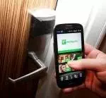 A person using a Samsung Galaxy S3 smartphone to open a door at the Olympic Games experience venue, utilizing the Holiday Inn app.